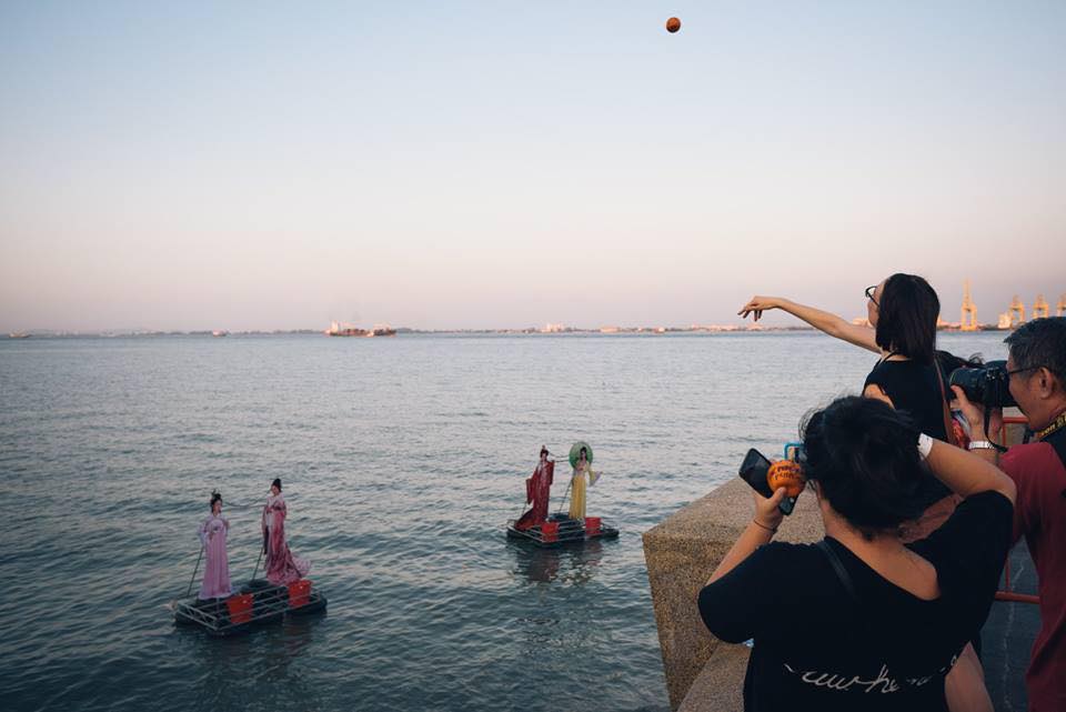 A woman tosses an orange into the sea during Chap Goh Meh at the Esplanade, Penang